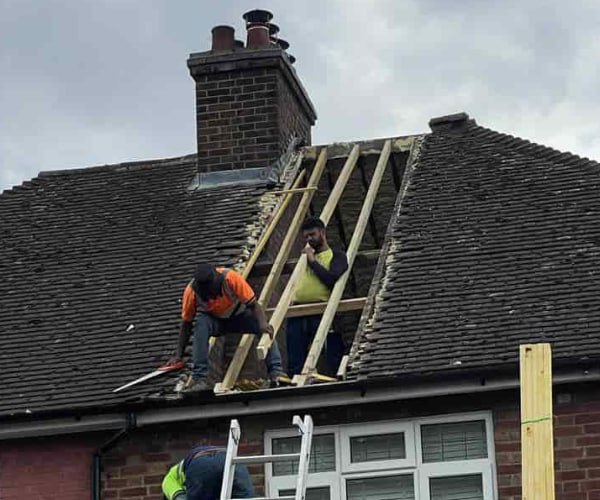 This is a photo of a roof repair being carried out. A section of the roof has been stripped and two roofers are replacing the rafters. Works being carried out by SAR Roofing Biggleswade