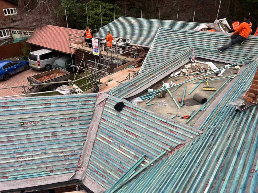 This is a photo of a large re-roof being carried out by SAR Roofing Biggleswade, there are multiple sections of pitched roofs adjoining to a central flat roof